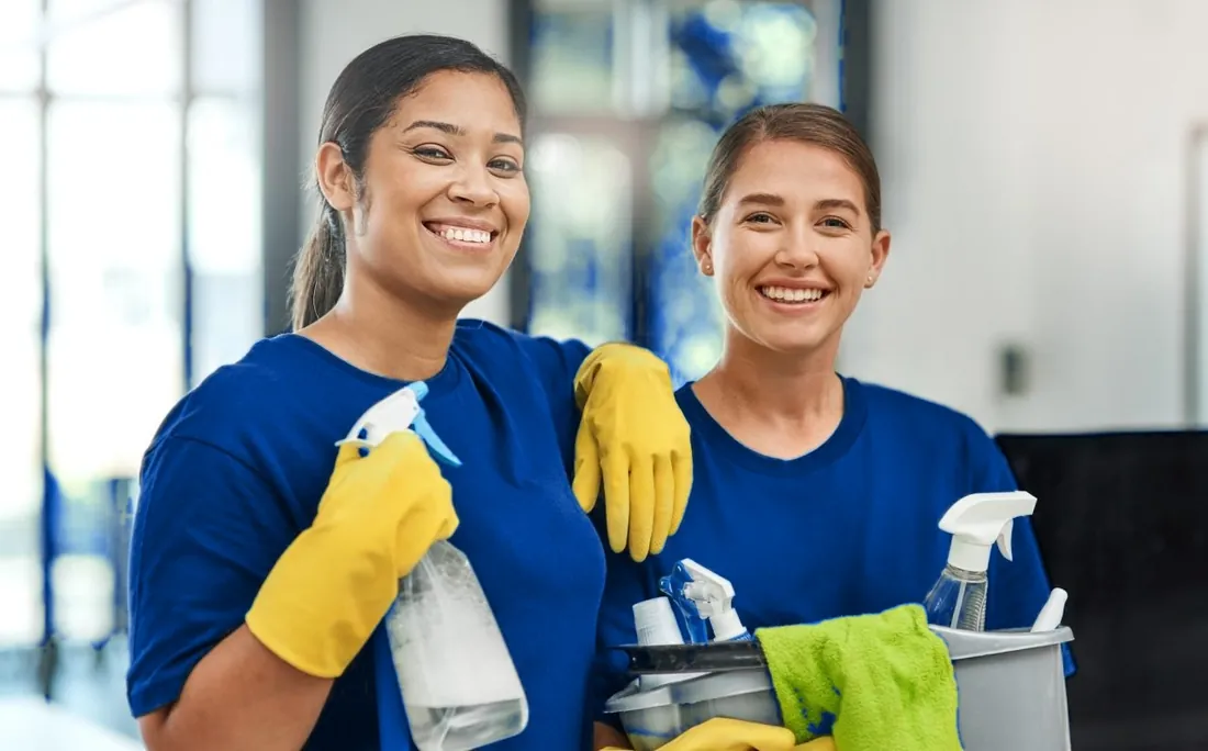 Two professional cleaners in blue shirts smiling