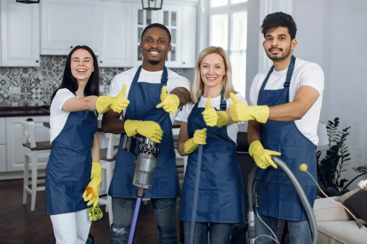 Smiling team of professional cleaners in blue uniforms